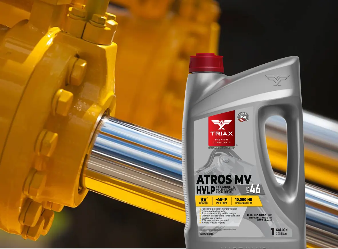 A bottle of TRIAX ATROS MV HVLP 46 motor oil stands in front of a yellow industrial pump or valve assembly. The bottle is silver with a red cap and features the TRIAX logo and product name clearly on the front label.