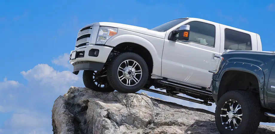 White pickup truck on a rocky outcrop with a clear blue sky